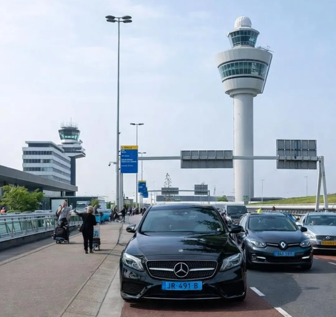 Zwarte taxi voor de verkeerstoren van Amsterdam Airport Schiphol